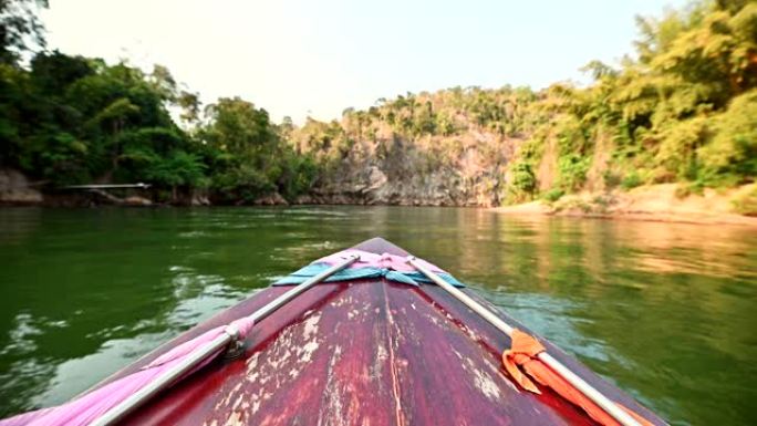 驾着长尾木船在桂河观光热带森林