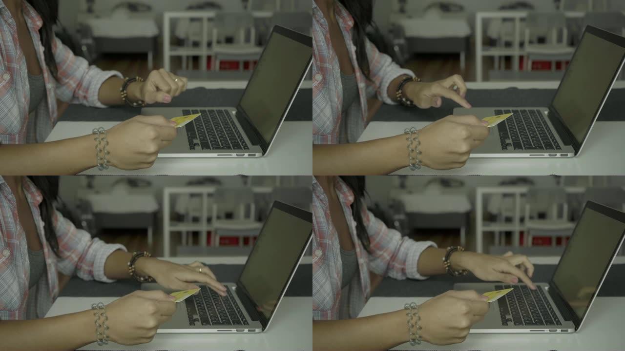 在笔记本电脑上剪过长发打字卡号的年轻女子的照片。