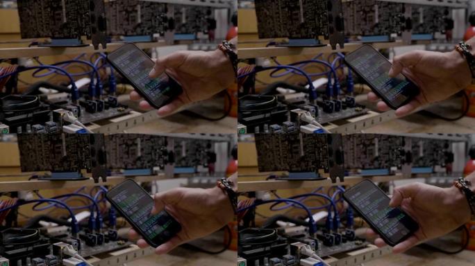 技术人员在gpu加密货币采矿设备附近的智能手机显示屏上显示采矿软件的进展