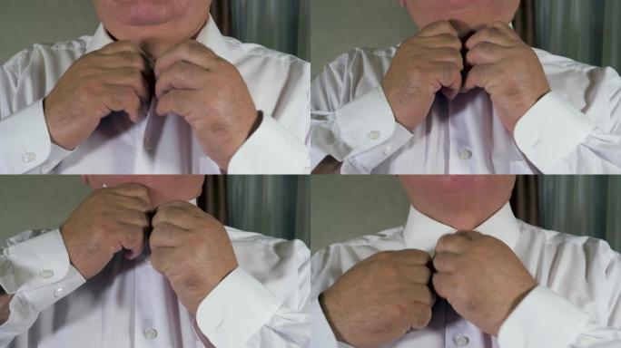成熟的男人双手系在白衬衫上的纽扣
