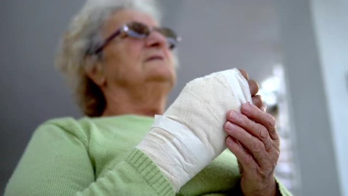 老妇人按摩她受伤的断手坐着，电影的dop