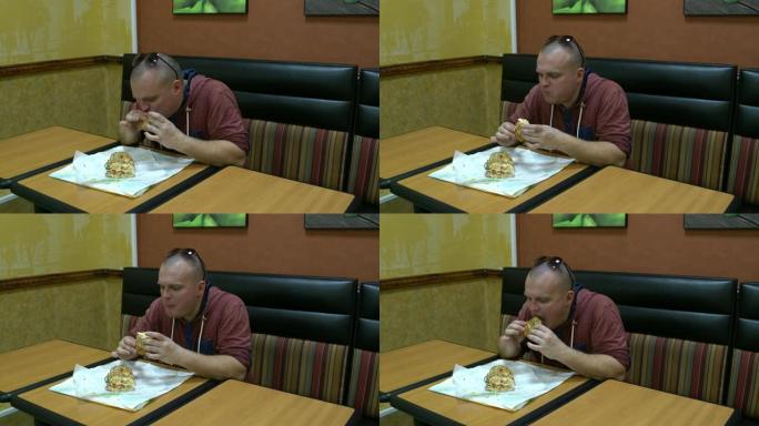咖啡馆里的男人坐在桌子旁吃三明治。