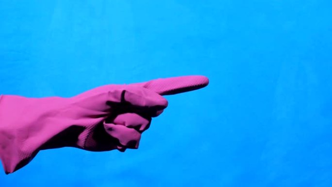 带有紫色橡胶手套的手指向蓝色背景