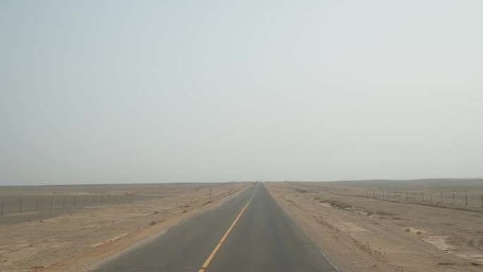 有人在空旷的沙漠道路上驾驶车辆的观点，高角度，快速模式，驾驶员视图。