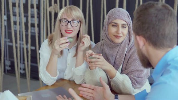 一个男人正在咖啡馆里跟两个阿拉伯和白人女人讲有趣的故事