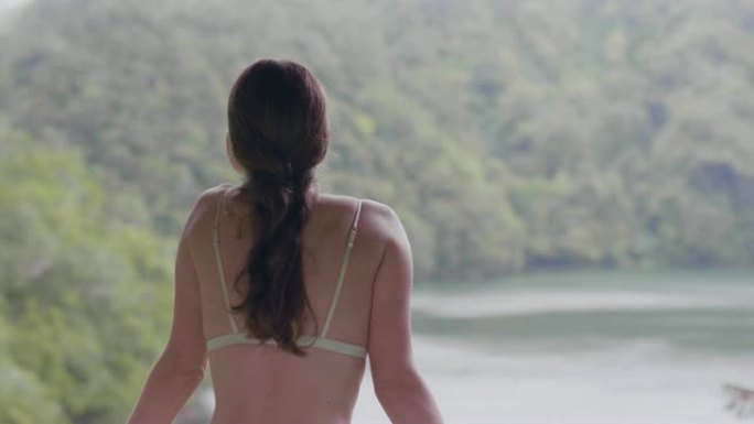 旅行的女人在绿色的山丘覆盖的热带森林中享受湖泊景观。从室外阳台看雨林景观的旅游女孩。