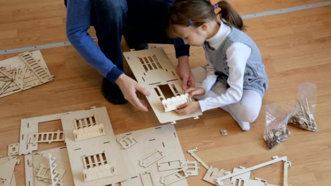 小女孩和父亲一起建造木制玩具屋