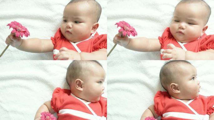 穿着红色衬衫的亚洲婴儿拿着花