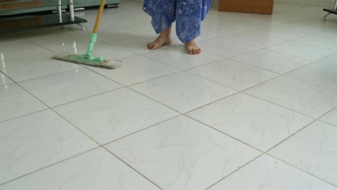 女人用拖把洗地板上的污垢