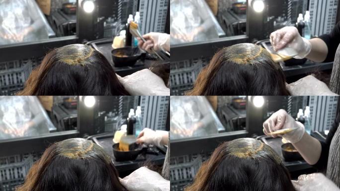 理发师在美容院的一个女孩的头发上涂上油漆。头发护理。特写。从顶部后部看到的景色。4 k.25 fps