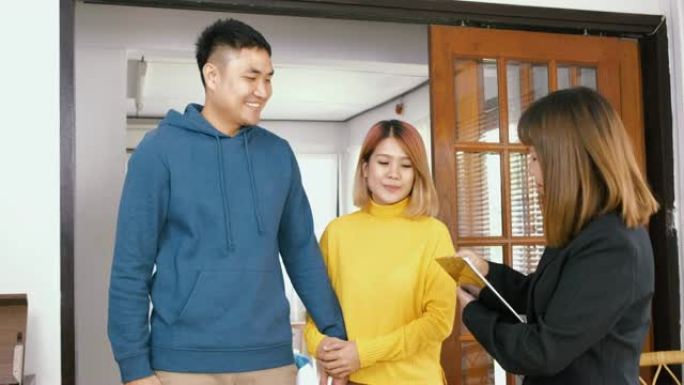 房地产经纪人向亚洲夫妇解释房屋，并在新家中给丈夫钥匙并互相拥抱。购买新房房地产