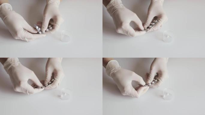 一名戴着白色乳胶手套的护士将药片从白色桌子上的水泡中挤出