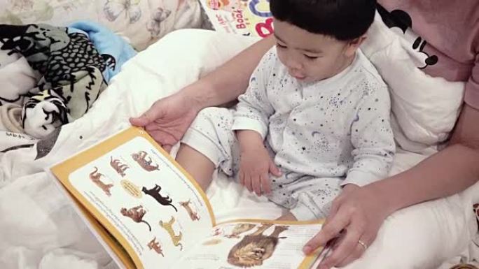 亚洲婴儿读书与母亲在床上
