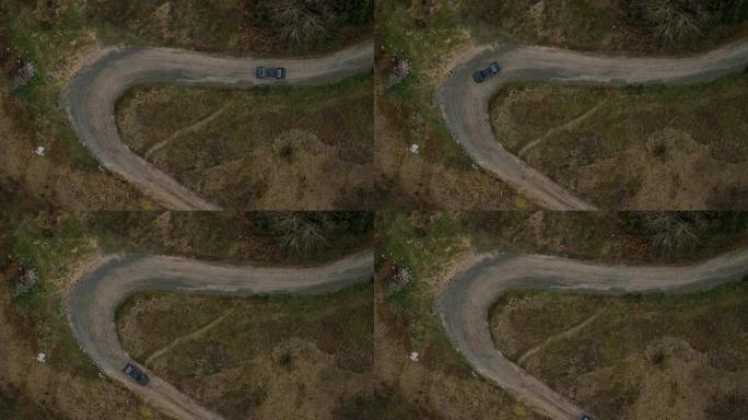 汽车在狭窄弯道上行驶的空中俯视图。旧黑色宝马在狭窄的乡村道路上的鸟瞰图