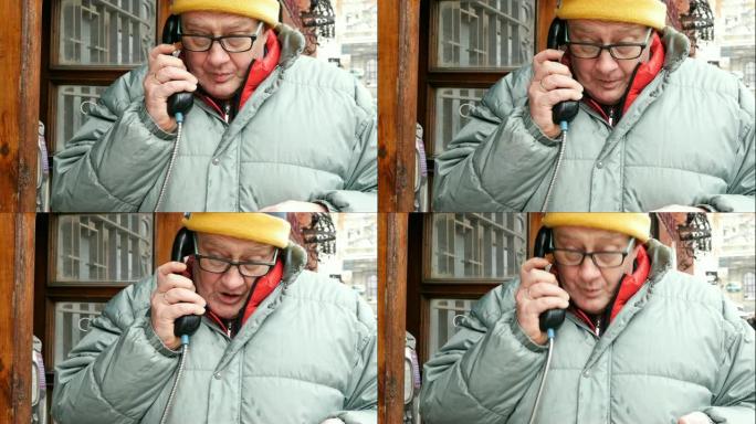 成年男子在街上的公共电话亭里用电话讲话。