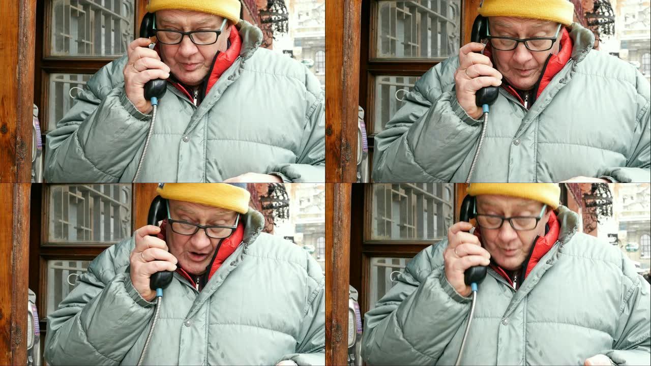 成年男子在街上的公共电话亭里用电话讲话。