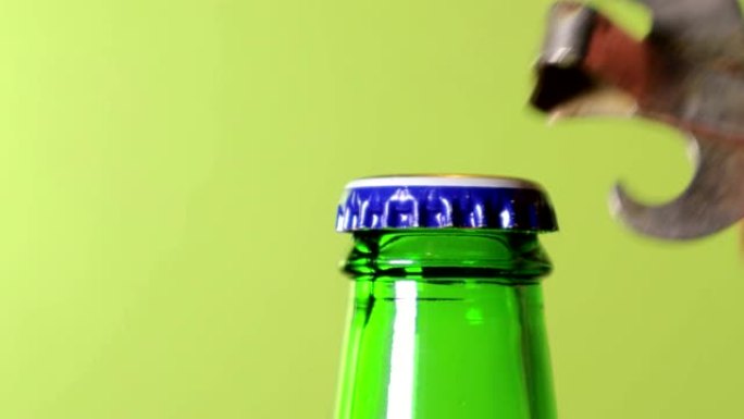 一只手在绿色的背景上打开一瓶绿色的啤酒。