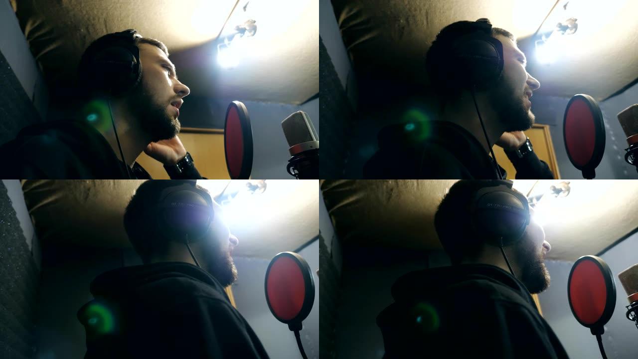 耳机男歌手在sound studio的麦克风中唱歌。年轻人在情感上录制新歌。创意音乐家的工作。展示商