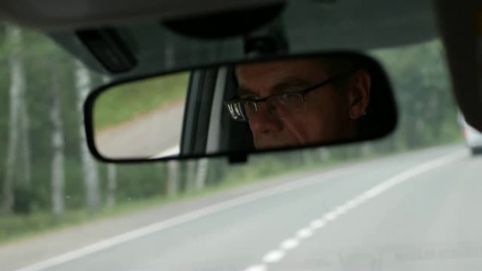 高级男子在乡间小路开车。汽车后视镜中面部的反射。特写。4k