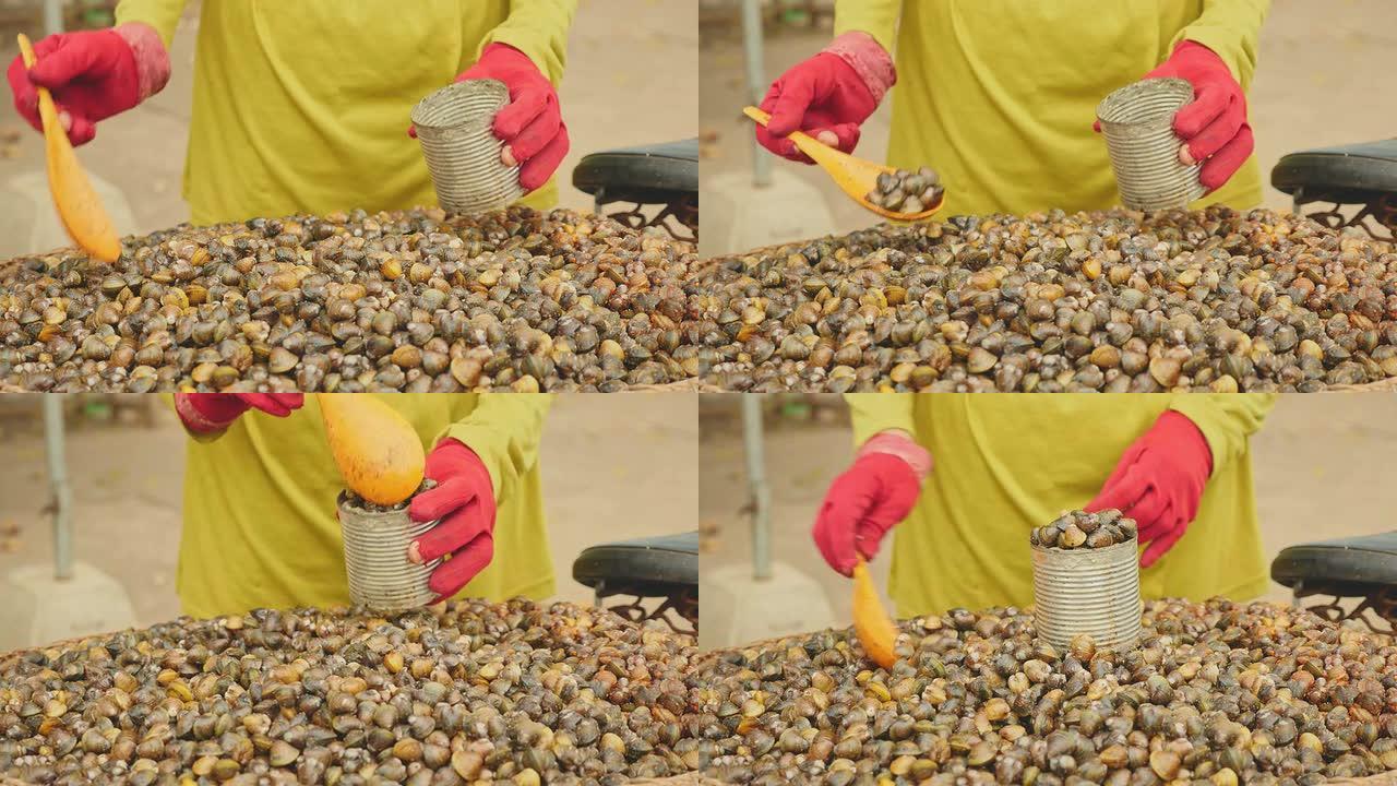 街头蛤蜊卖家的特写镜头，用塑料勺子把蛤蜊放在锡罐里测量份量