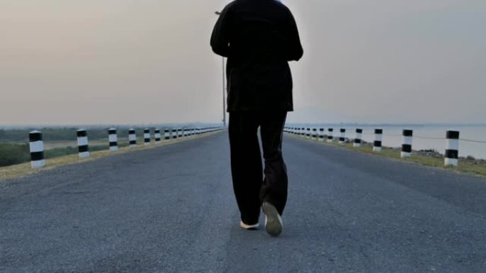 资深亚洲男性晚上在路上慢跑。通过运动过上健康的生活方式。慢动作