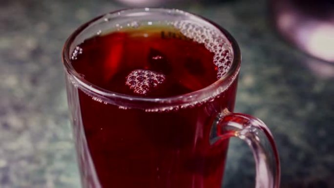 茶包浸泡在一杯茶中，并与不锈钢勺子混合特写