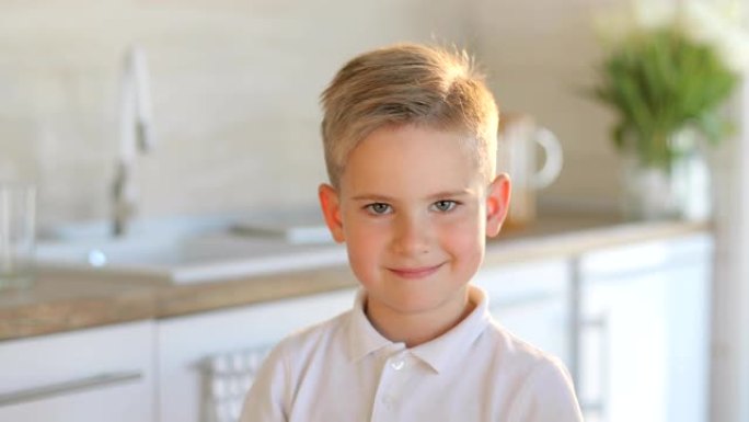 可爱的年轻快乐男孩看着相机的肖像。孤立在白色厨房背景上。小男孩微笑着向前看。