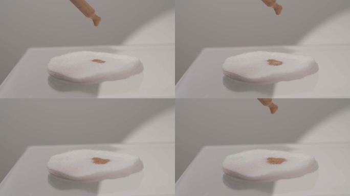 滴落在白色背景上的棉垫上的色调奶油的特写镜头。
