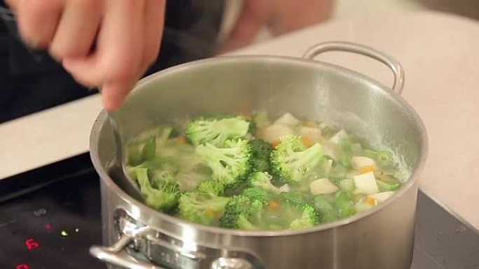 厨师正在将西兰花放入沸腾的蔬菜汤中