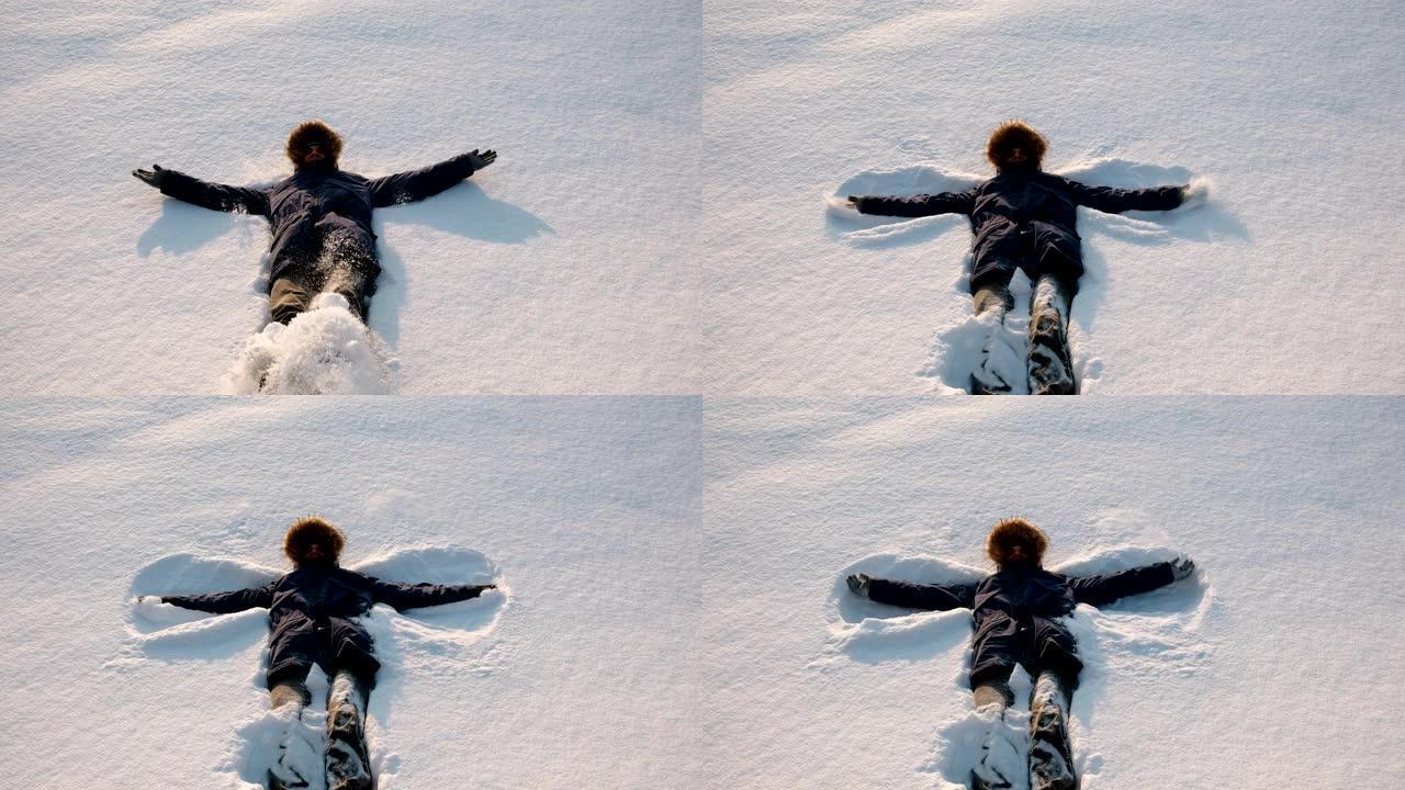 穿着蓝色羽绒服的男人和毛皮兜帽做了一个雪天使。