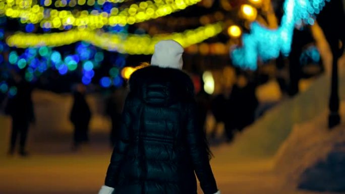 女人冬天穿着夹克和帽子在公园散步。后视摄像头。