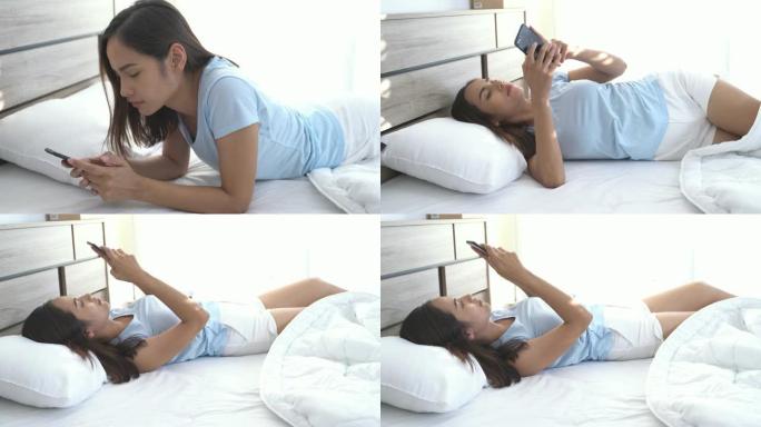 亚洲女性她躺在床上，用手机。