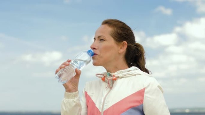 女人在海滩上锻炼后喝水
