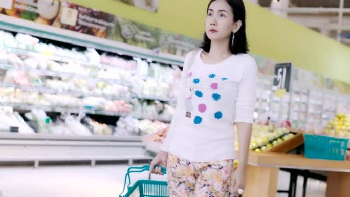 年轻的亚洲妇女在超市里买了许多水果和食物。