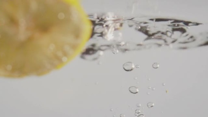 一片柠檬在清澈的水中落下慢动作