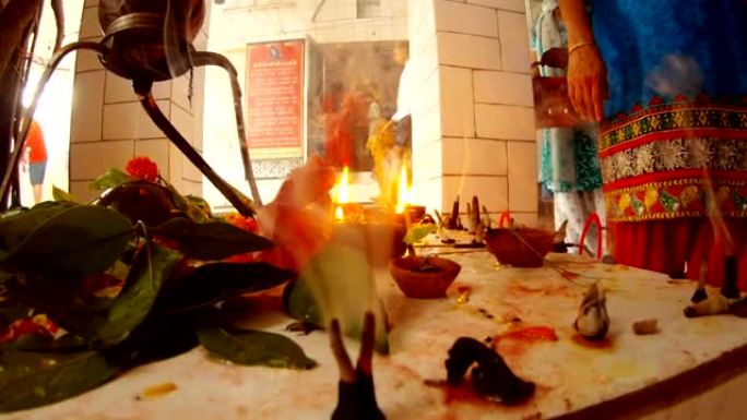 鲜花中的小林格木绿叶蜡烛和传统印度服装的人进入背景瑞诗凯诗的寺庙