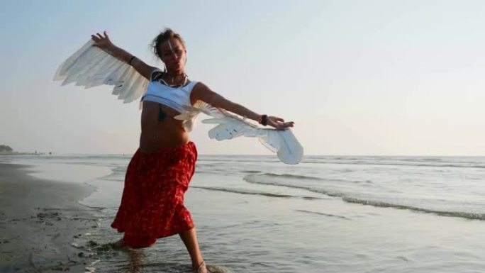 带着天使翅膀的年轻女孩在日落时跳舞