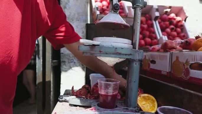 石榴卖家压水果。石榴汁在旧金属榨汁机上制备，特写。