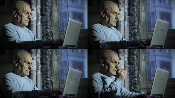 老人深夜抽烟时在电脑上工作