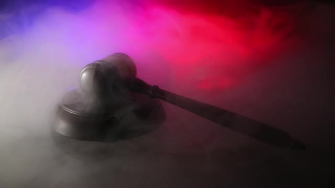 法律主题，法官木桌上的木槌，带有大法官雕像。法律木槌在黑暗的有雾背景下。选择性聚焦
