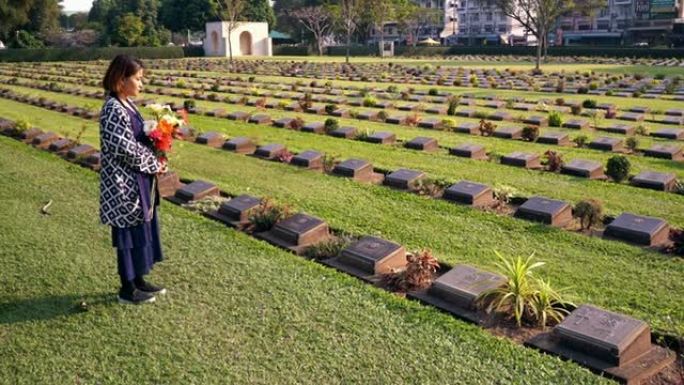 泰国北碧府，游客带着鲜花参观二战墓地。