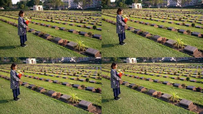 泰国北碧府，游客带着鲜花参观二战墓地。