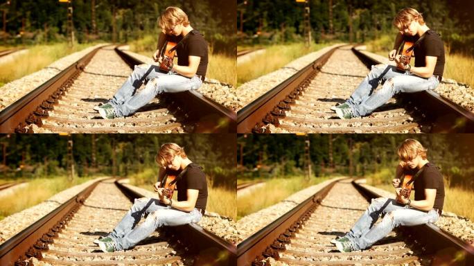 长发吉他手坐在铁路上弹吉他