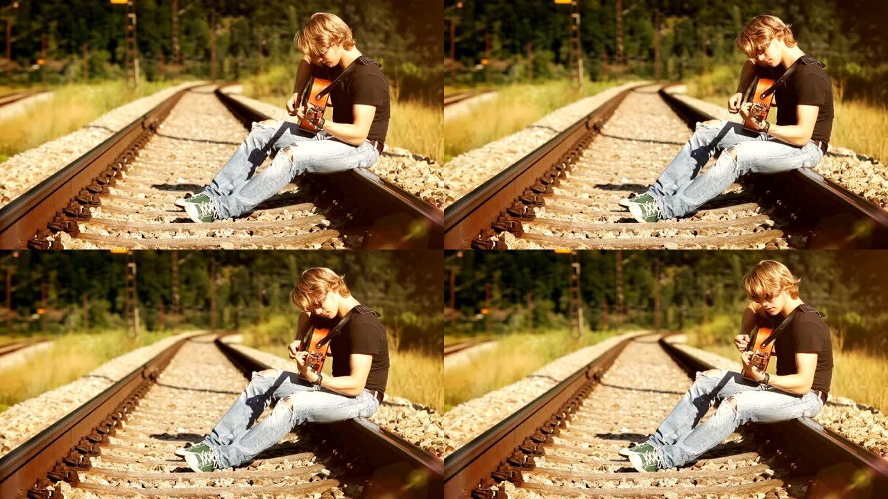 长发吉他手坐在铁路上弹吉他