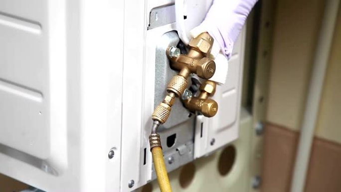 空气机械师固定并安装组装并将冰箱氟利昂气体填充到客户房屋的压缩机空气通道黄铜管中。