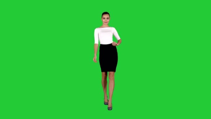 魅力时尚女性布鲁内特自信地走在绿色屏幕上，色键