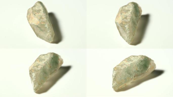 白色背景旋转的多夹杂物水晶 (花园水晶) 矿物石材样品