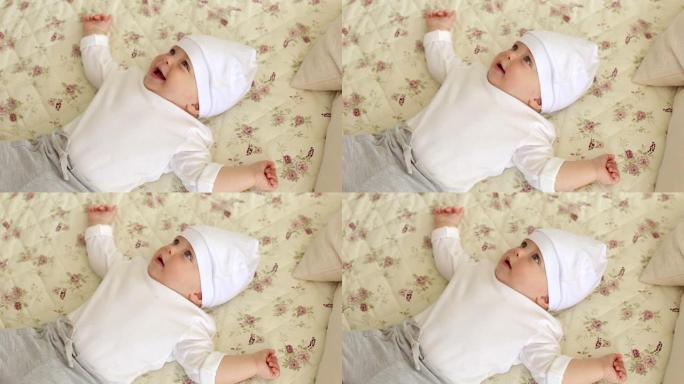 一个戴着白帽子的新生可爱的男孩躺在家里的床上的特写镜头。