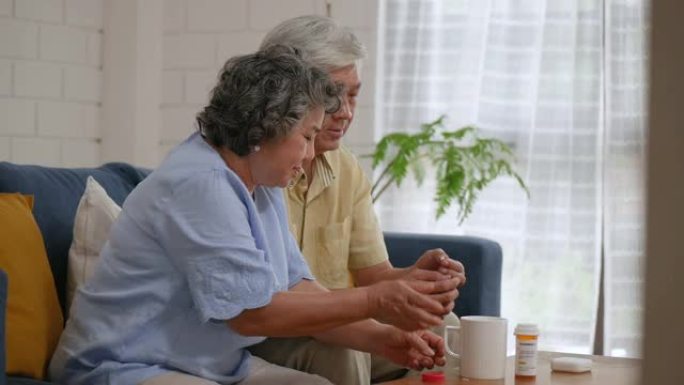 亚洲老年夫妇老人吃药，在家客厅喝水。