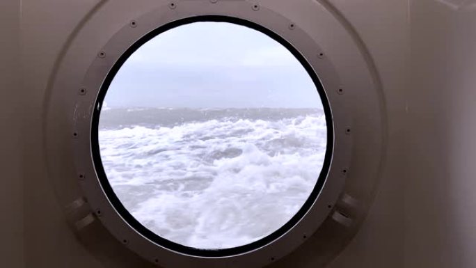 透过波涛汹涌的大海上的舷窗，海浪冲击着船